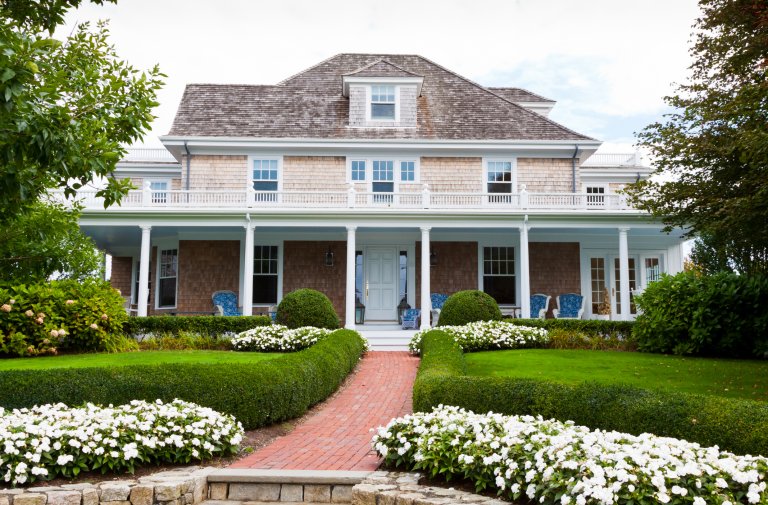 Beautifully landscaped front yard with flowers, lush grass and bushes is in foreground.