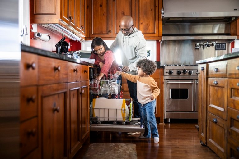 A family loading the dishwasher together.