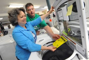 Woman and man reading the EnergyGuide sticker on a washing machine