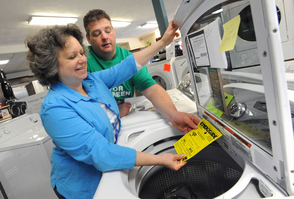 Woman and man reading the EnergyGuide sticker on a washing machine