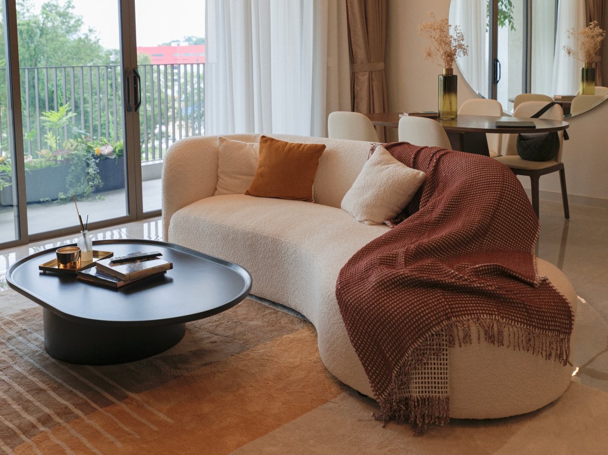 Curved sofa with neutral cushions and a brown throw blanket.