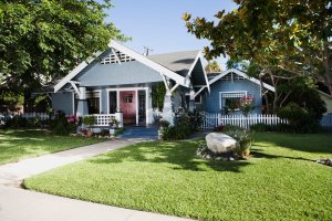 Blue Craftsman home exterior and front yard with a white picket fence