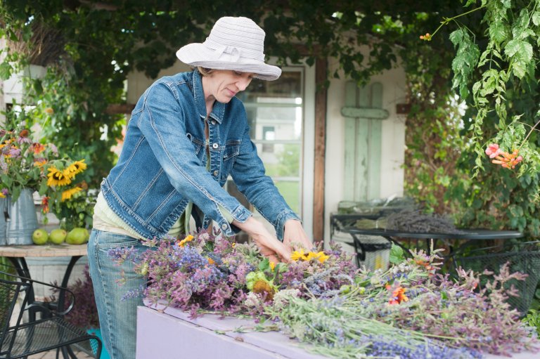Woman with white hat making herbal bouquets and wreaths