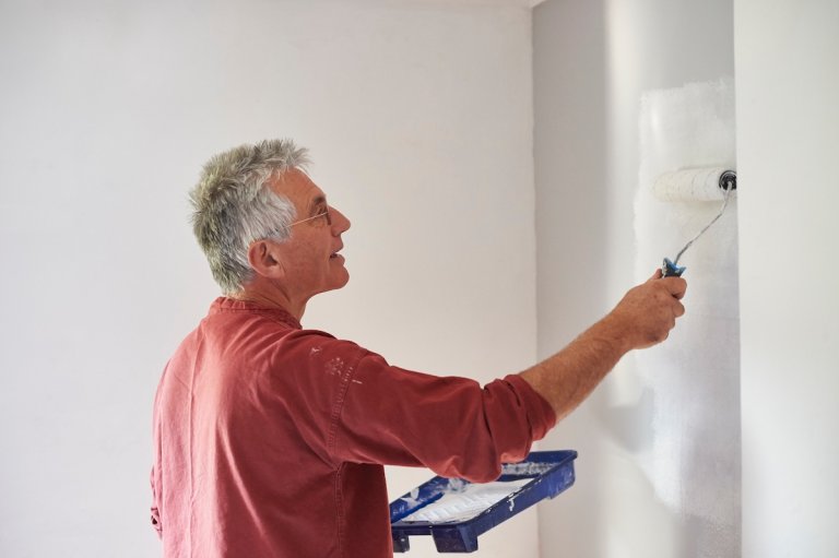 A DIYer painting walls in a bedroom.