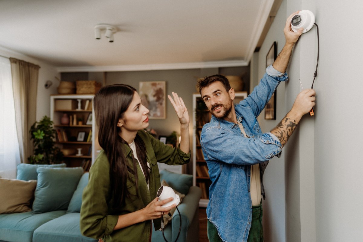 Young couple assembling camera security system in their house