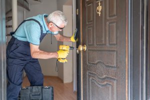Locksmith changing door locks using cordless drill in a house entrance