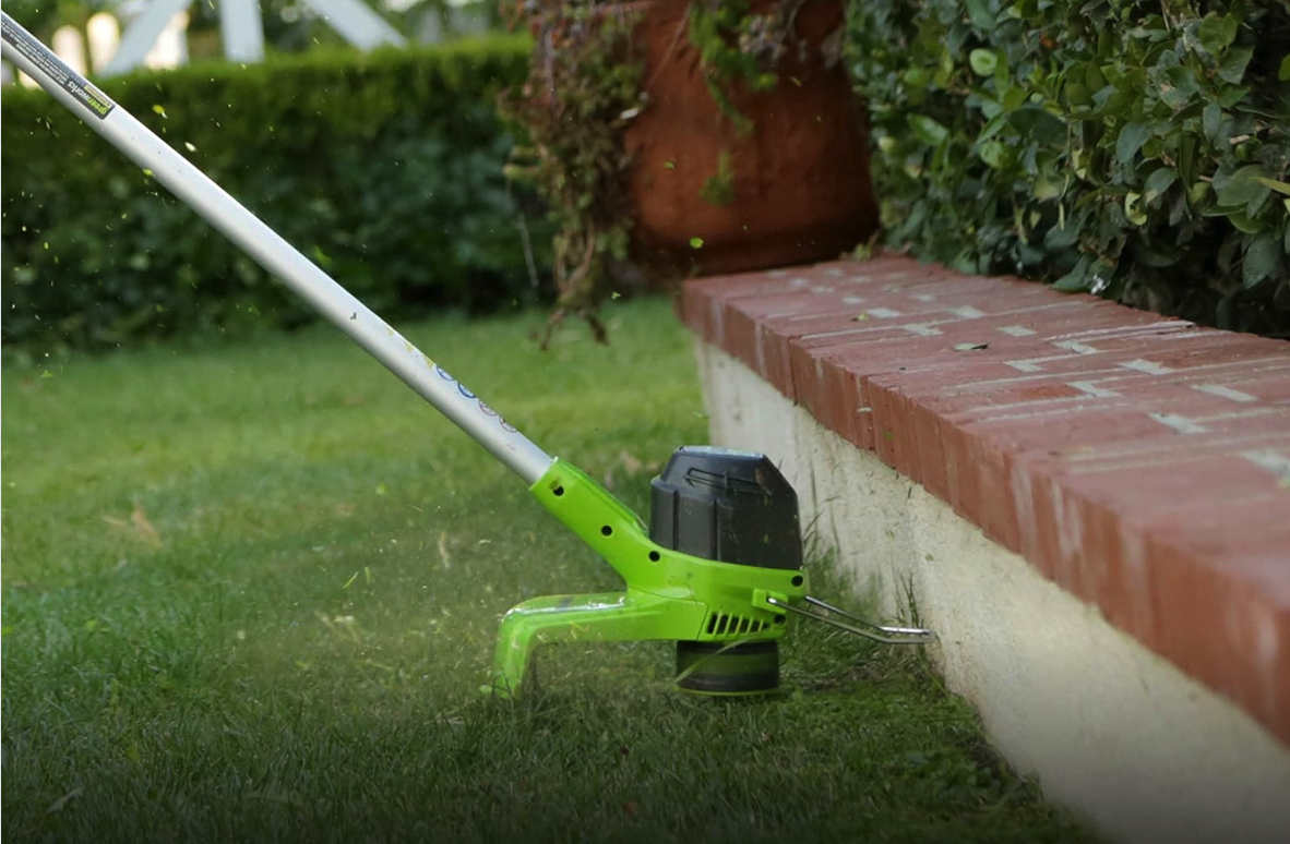 Greenworks string trimmer being used along a concrete barrier