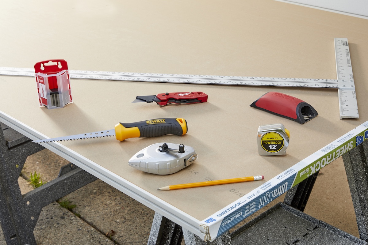 A group of drywall cutting tools on two sheets of drywall