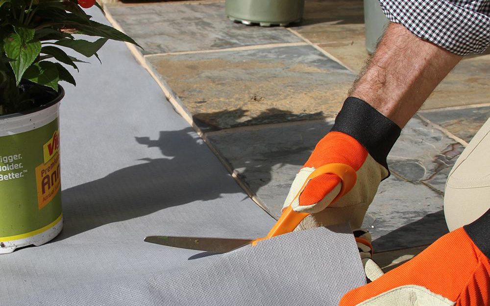 Landscaper cutting and installing landscape fabric