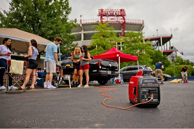 The Honda EU2200i 2200W Portable Inverter Generator in the foreground of a tailgating event with people in the background