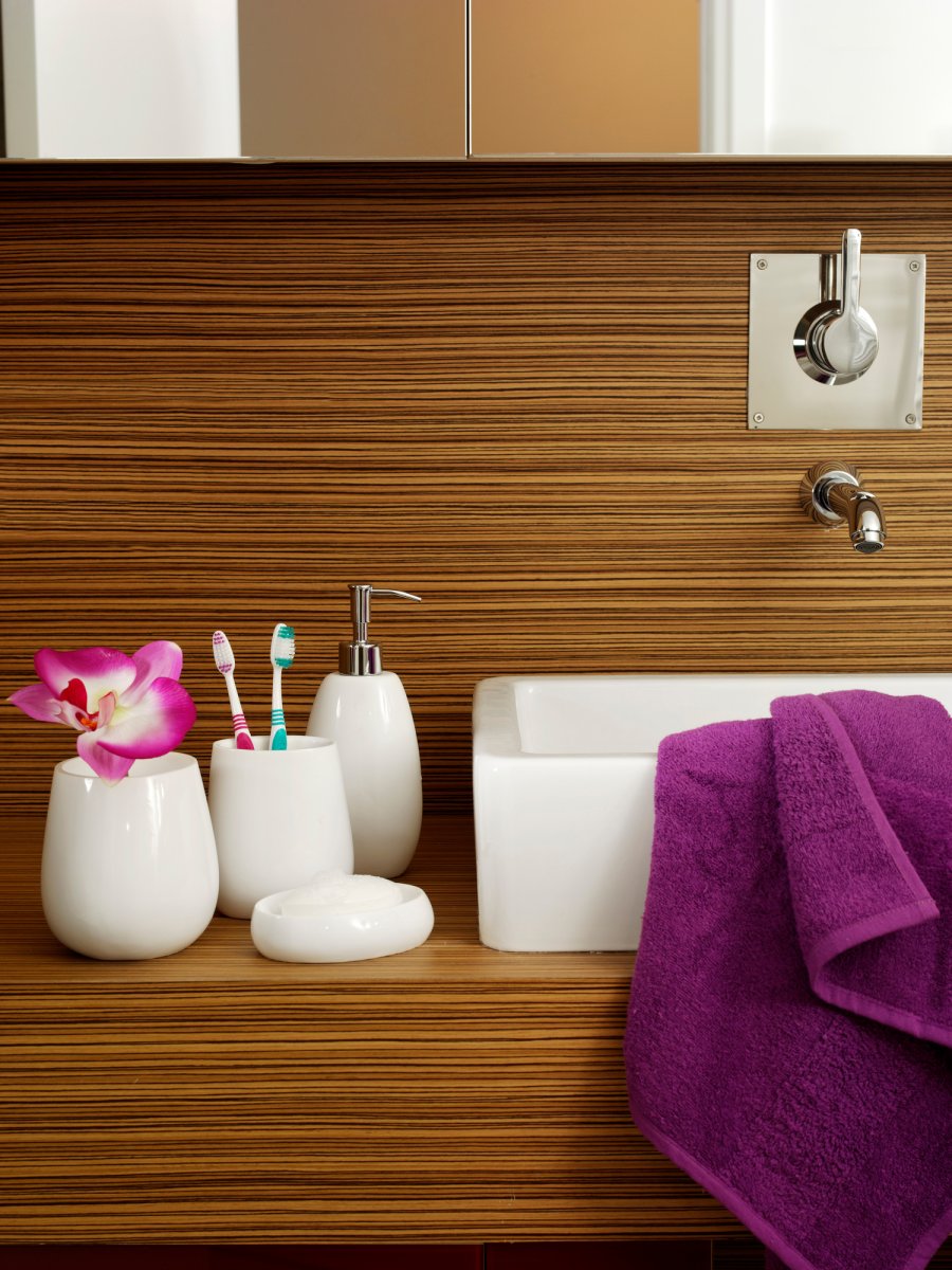 Modern bathroom counter and sink with toothbrushes in a toothbrush holder out on the countertop.