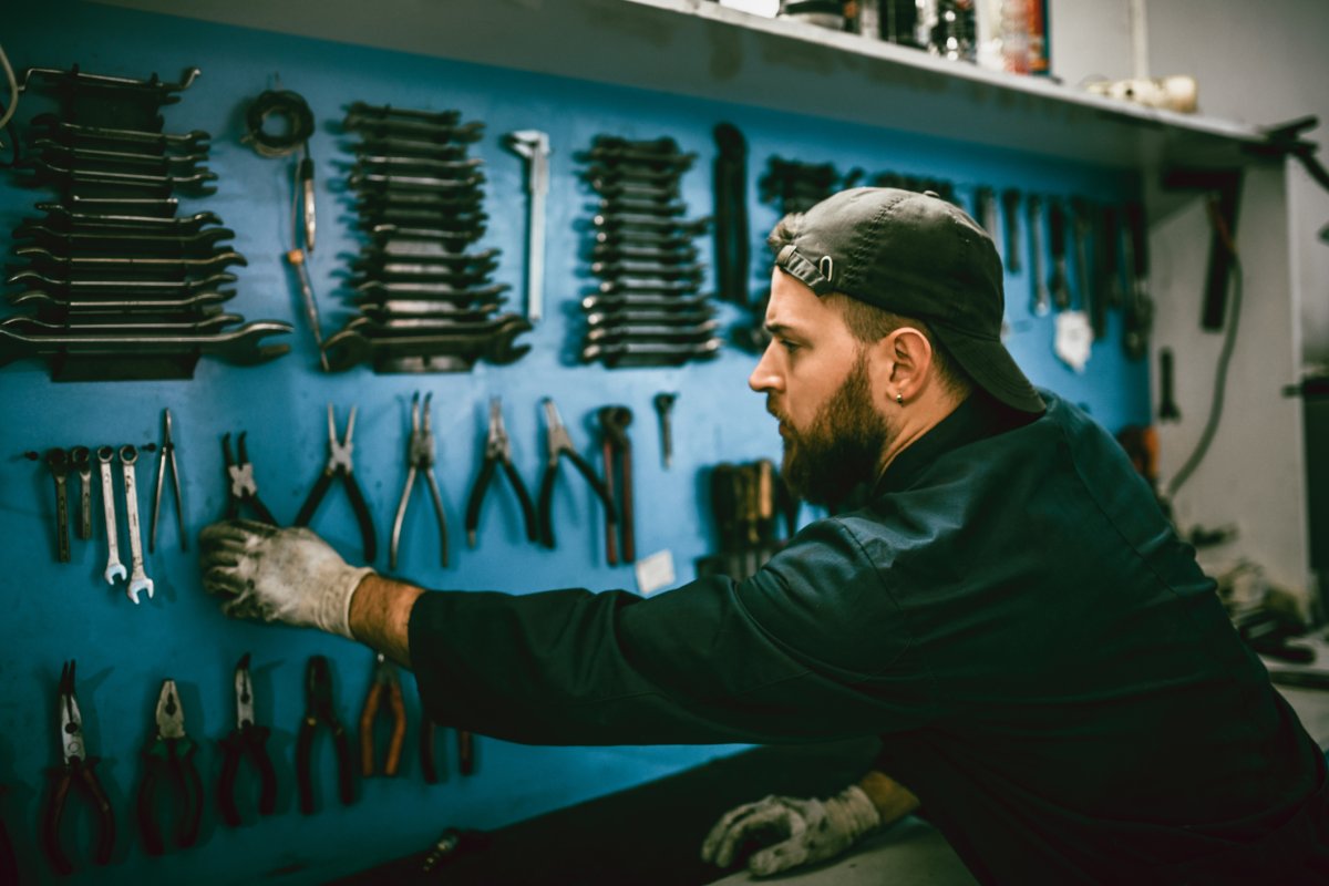 Man standing in front of a wall filled with different hanging tools.