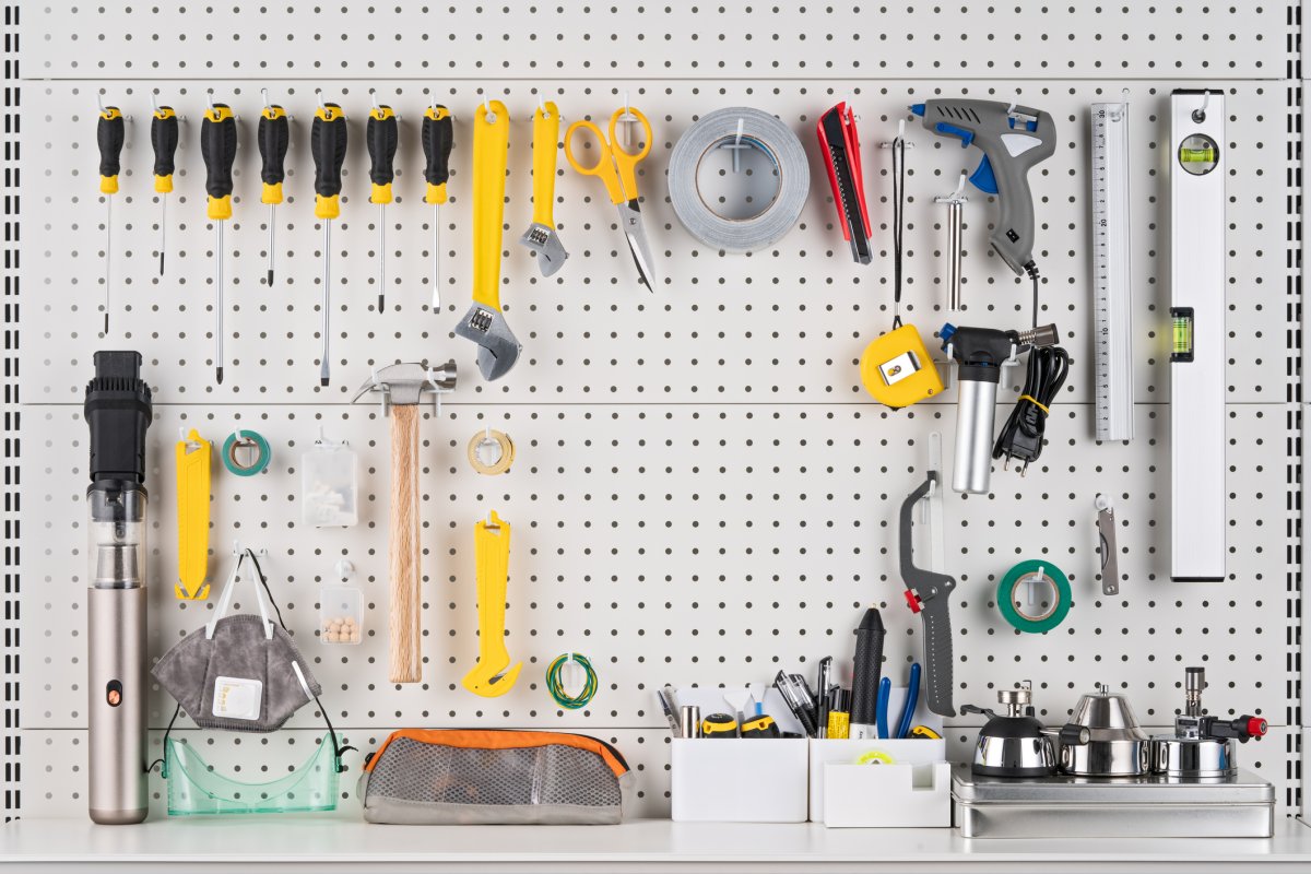 Various tools hanging on a white pegboard.