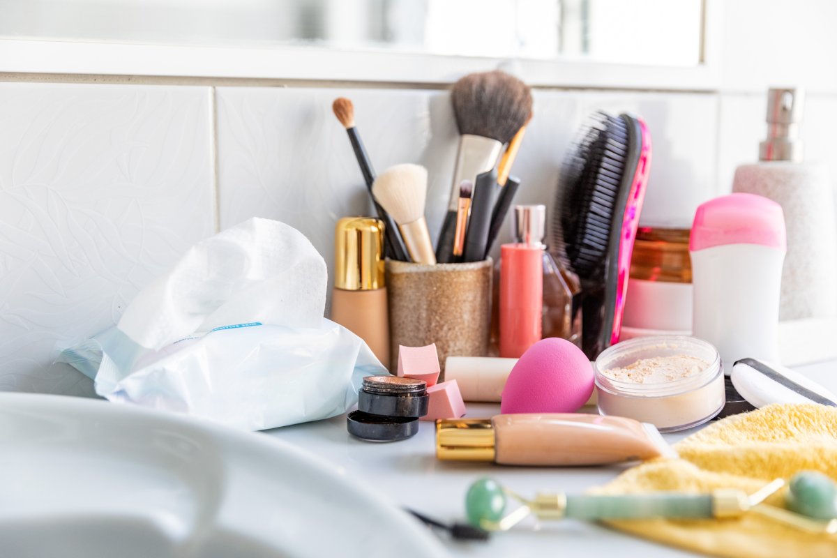 Messy cosmetics displayed on a bathroom countertop.