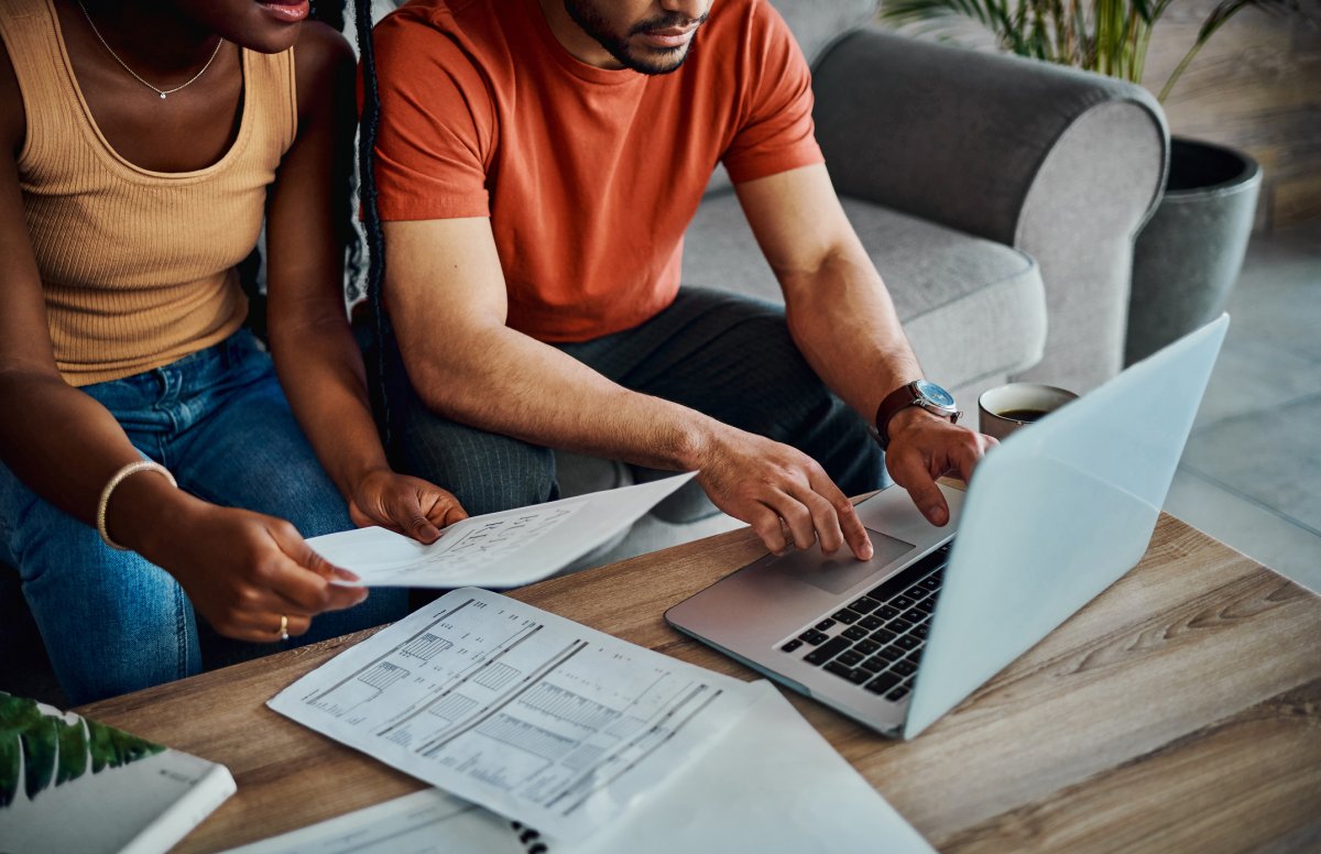 Couple sitting in front of a laptop with paperwork such as receipts to file their their taxes.