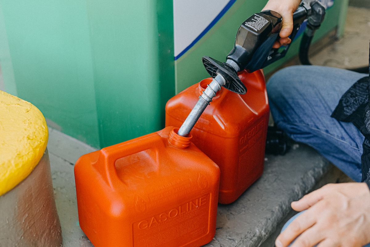 A person filling a gas can at a gas station.