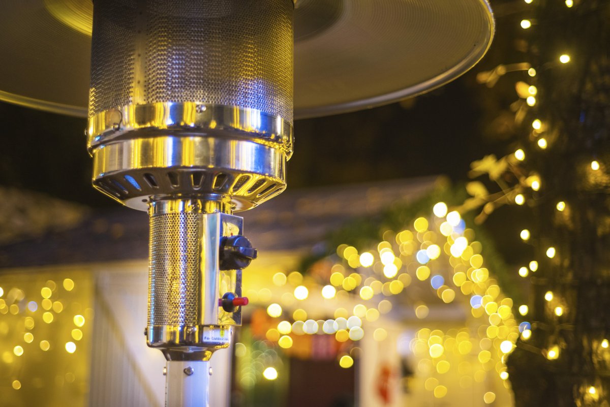 Closeup of stainless steel metal gas burning patio heater with blurred outdoor background