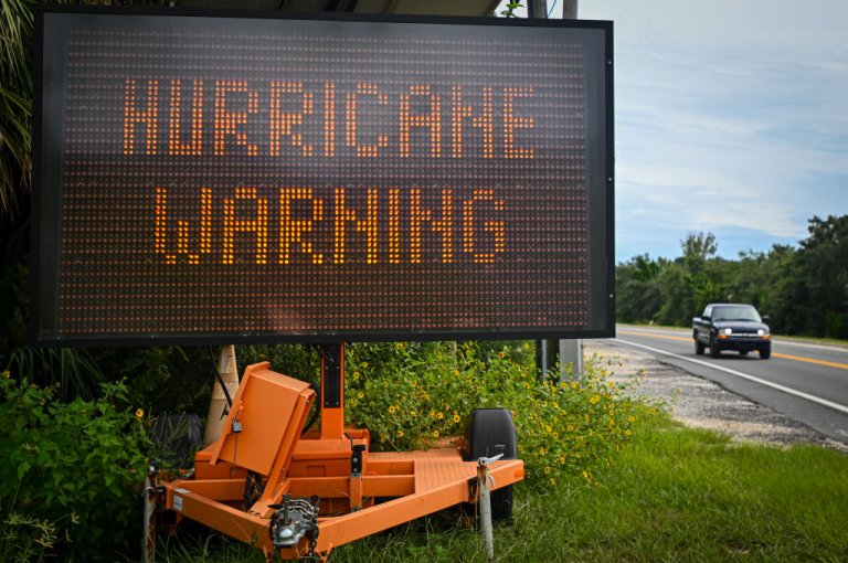 A sign displays a hurricane warning along a roadside.
