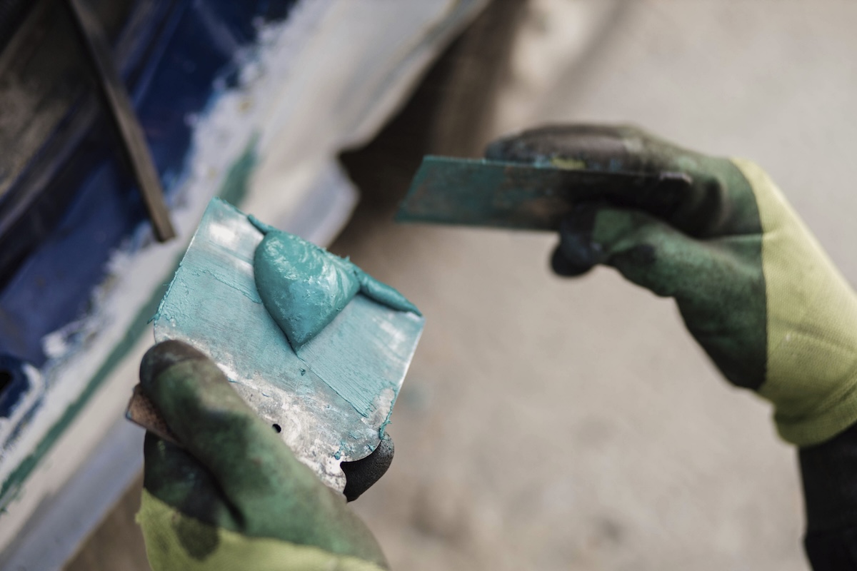Hands mixing Bondo autobody filler on a putty knife.