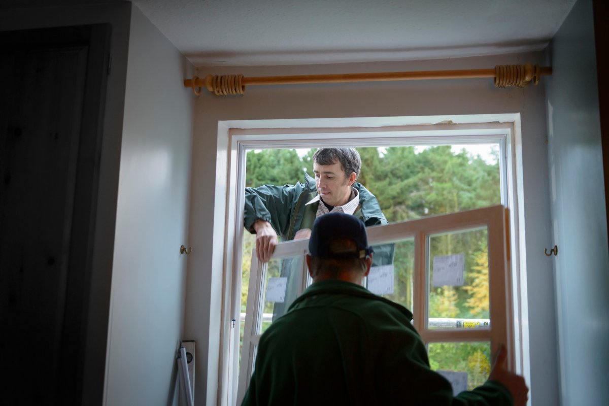 Two men installing a new window in a house