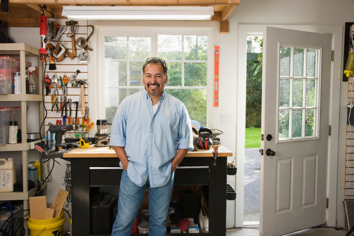 Smiling man in organized garage workshop.