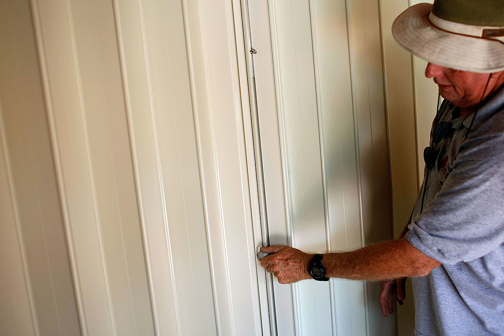 Man testing hurricane shutters on his house.