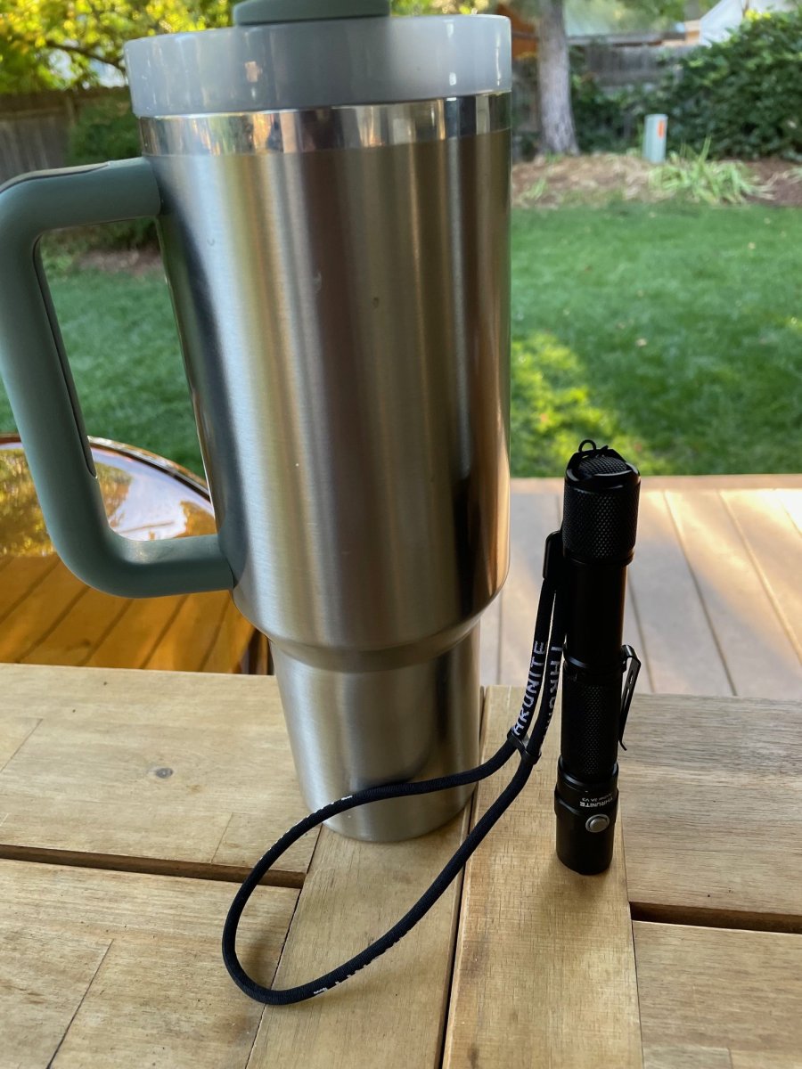 ThruNite Archer 2A V3 flashlight next to reusable cup for scale