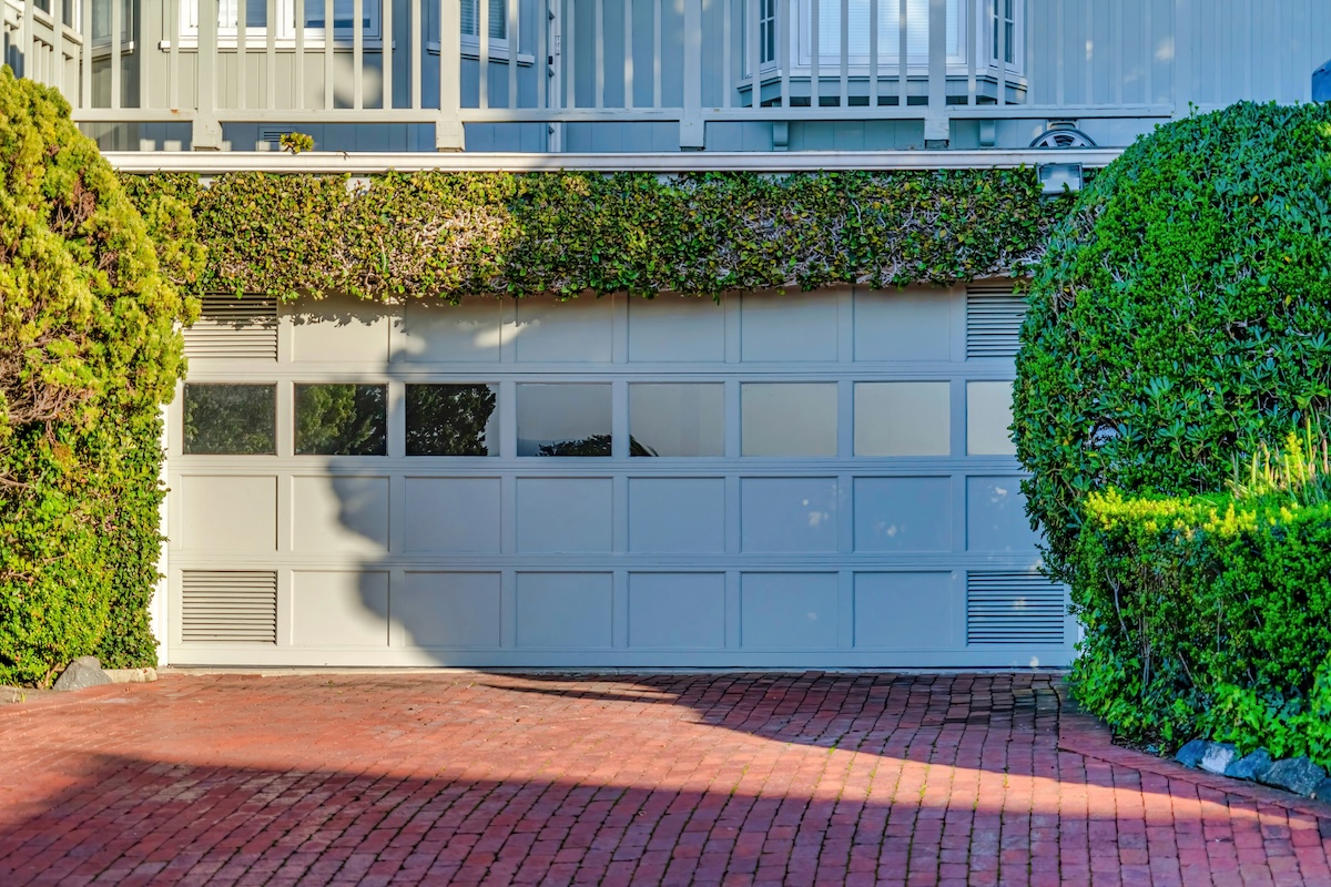 A red brick driveway and white garage door.