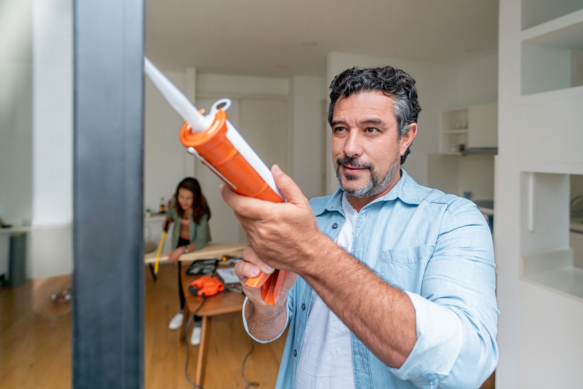 Man caulking around a door.