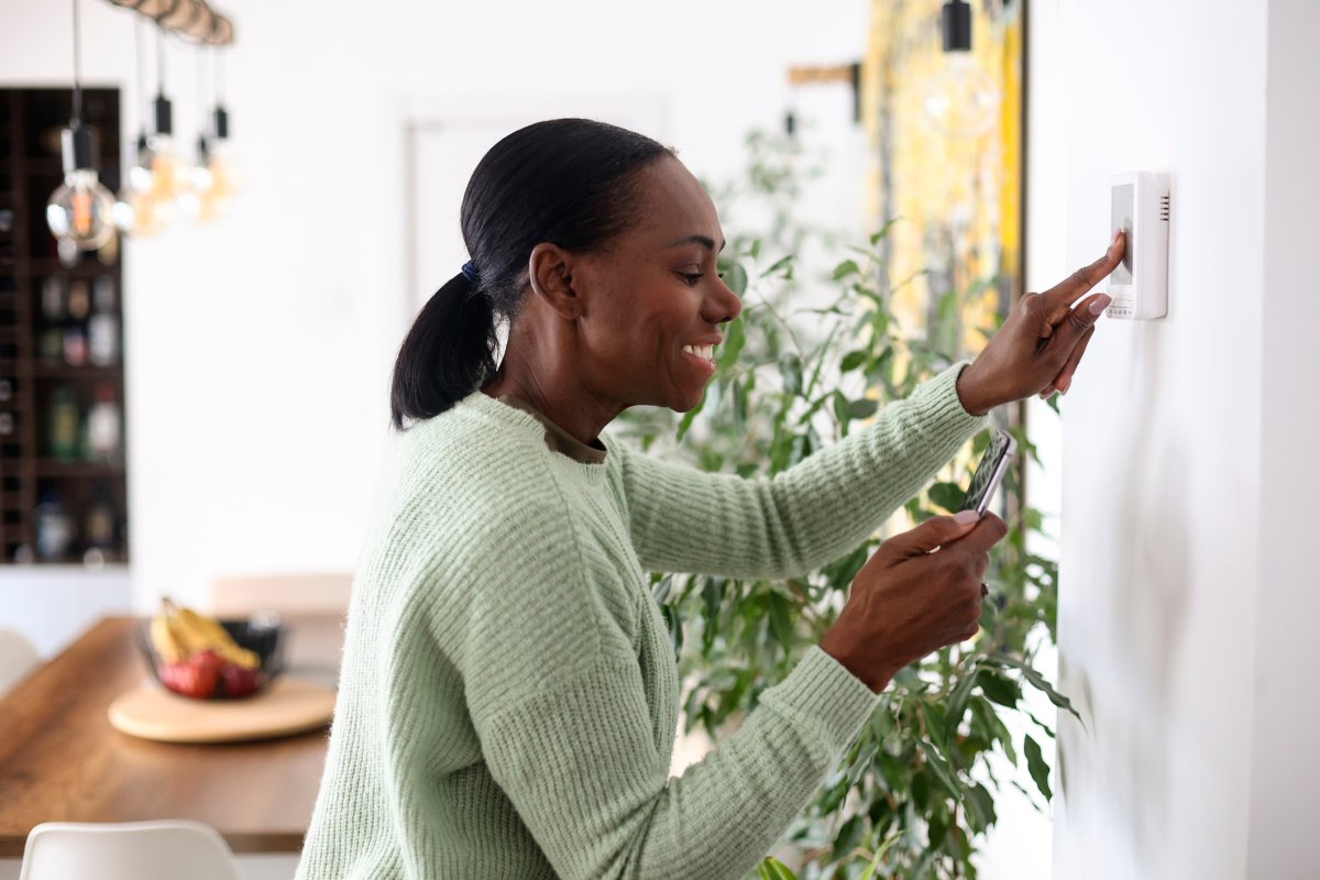 Woman adjusting the thermostat in her smart home.