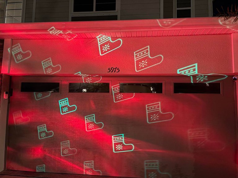 Govee Christmas light projector displaying white stockings on a red background