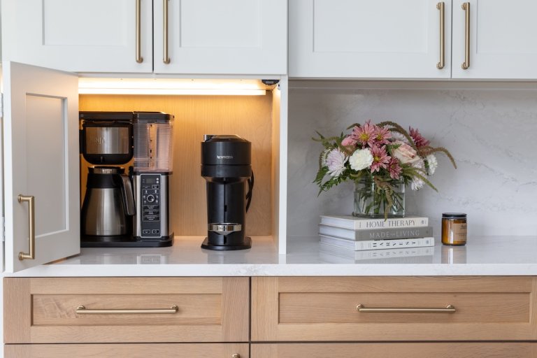An appliance garage in a modern kitchen with inside cabinet lighting.