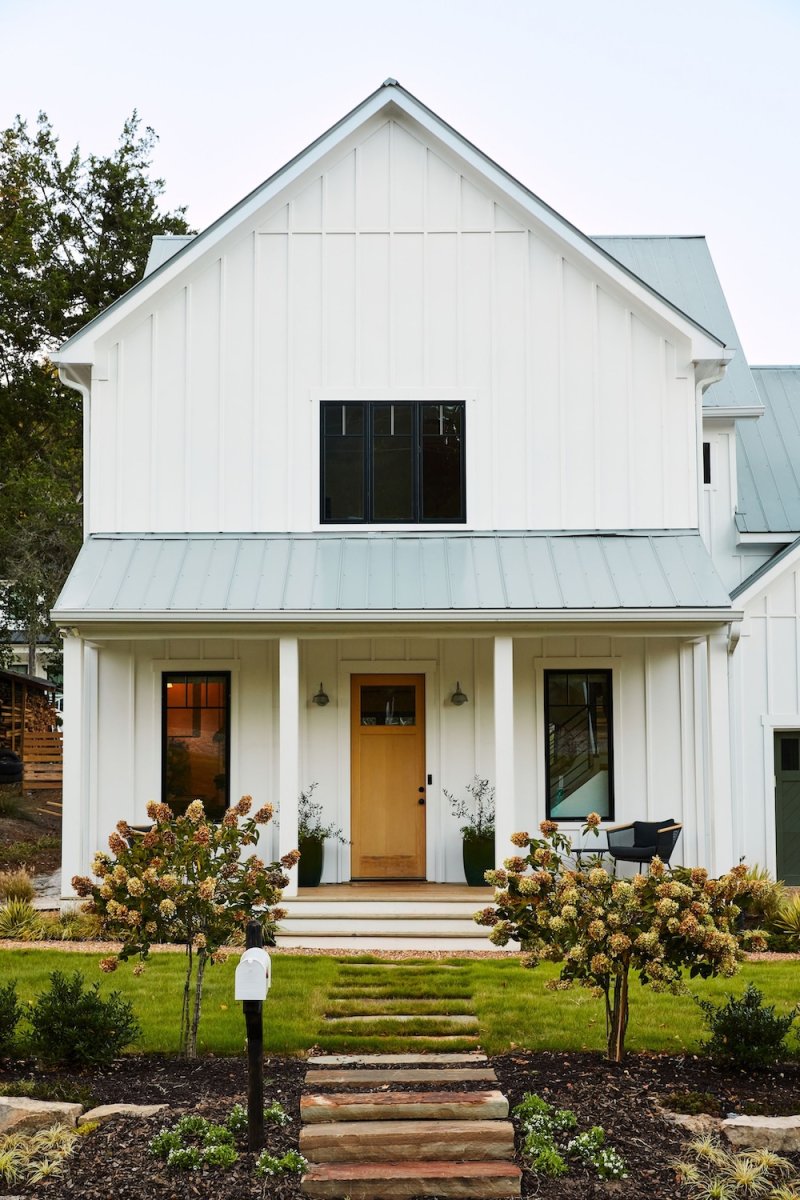 A white farmhouse with yellow front door and open porch.