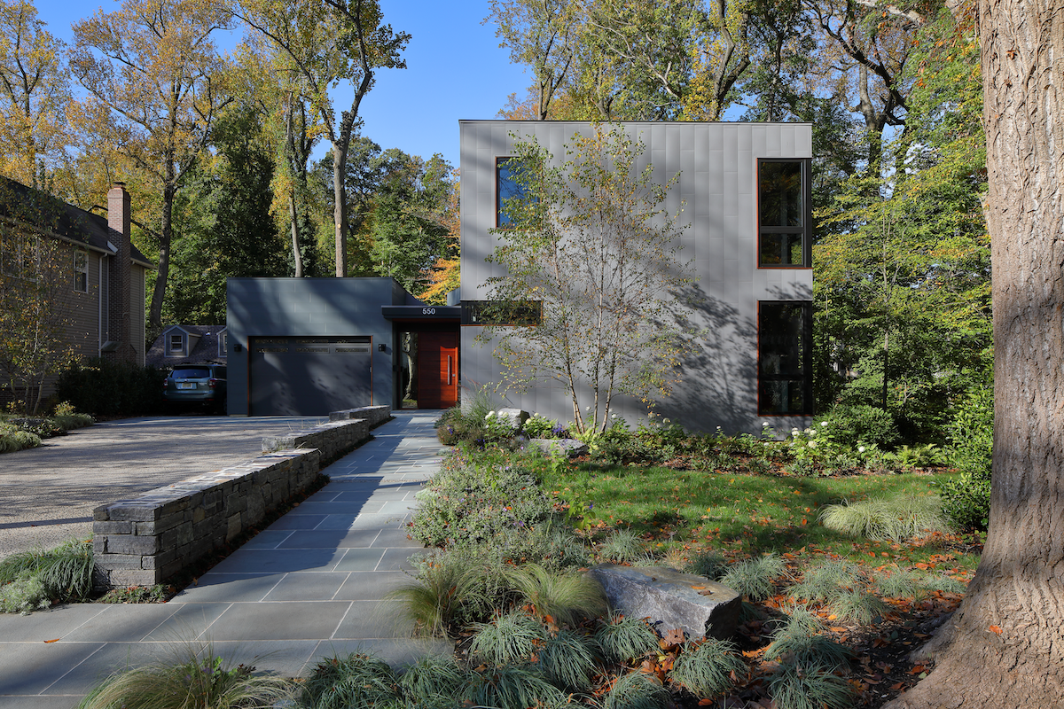 A rectangular, modern grey home with a red front door.
