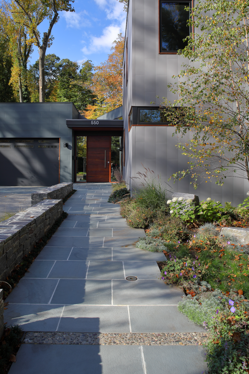 A modern home with a stone walkway leading to a cedar front door.