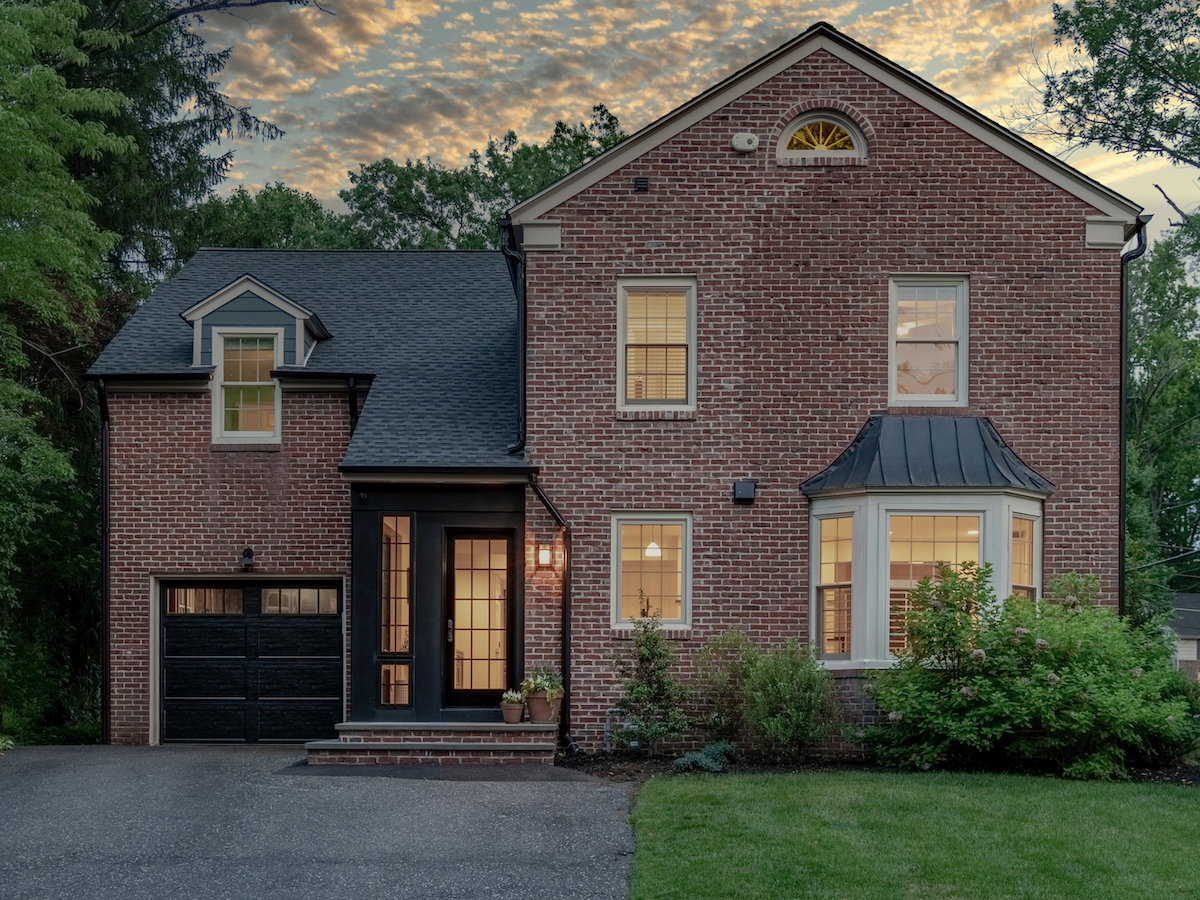 A traditional red brick home with a porch featuring modern fixtures.