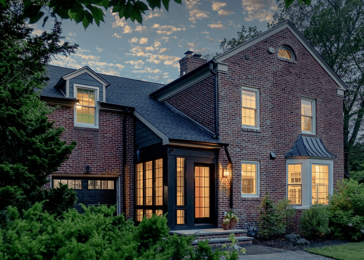 A red brick home with red brick, bright windows, and modern front porch awning.