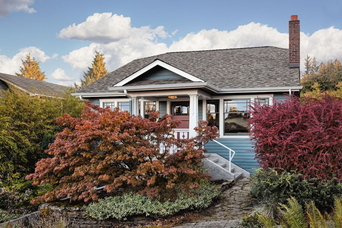 A blue home with a front porch supported by columns.