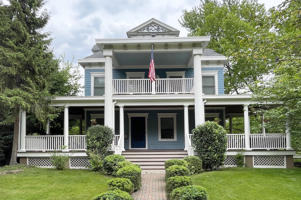 Blue two-story house with a white front porch and pillars.
