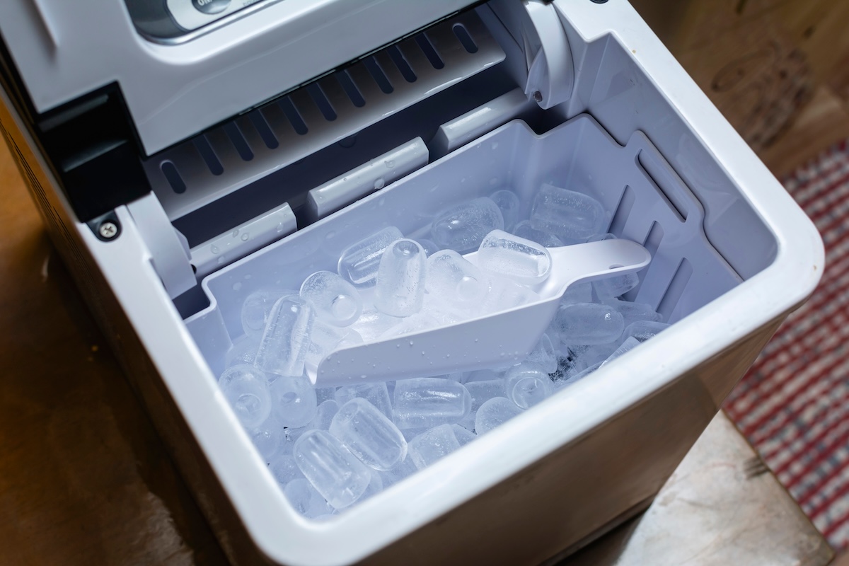 A small, countertop ice maker sits on a countertop.