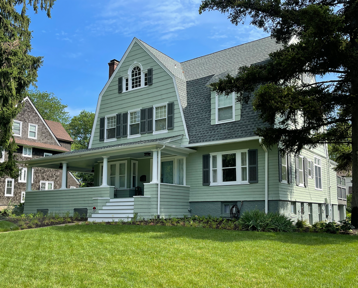 Two-story muted green house with black shutters.