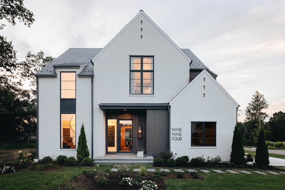Modern light grey house with black window frames and house number spelled out.