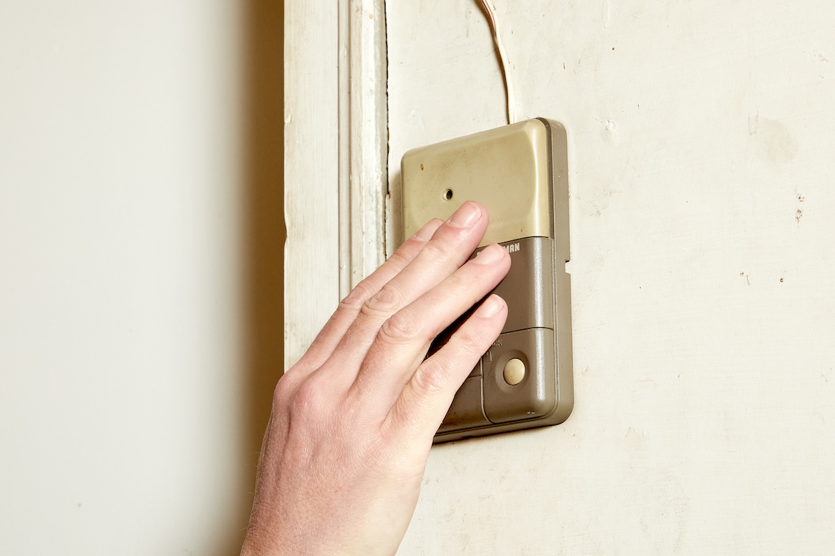 A person's hand lighting pushes an interior garage door opener.