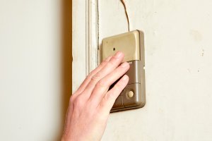 A person's hand lighting pushes an interior garage door opener.