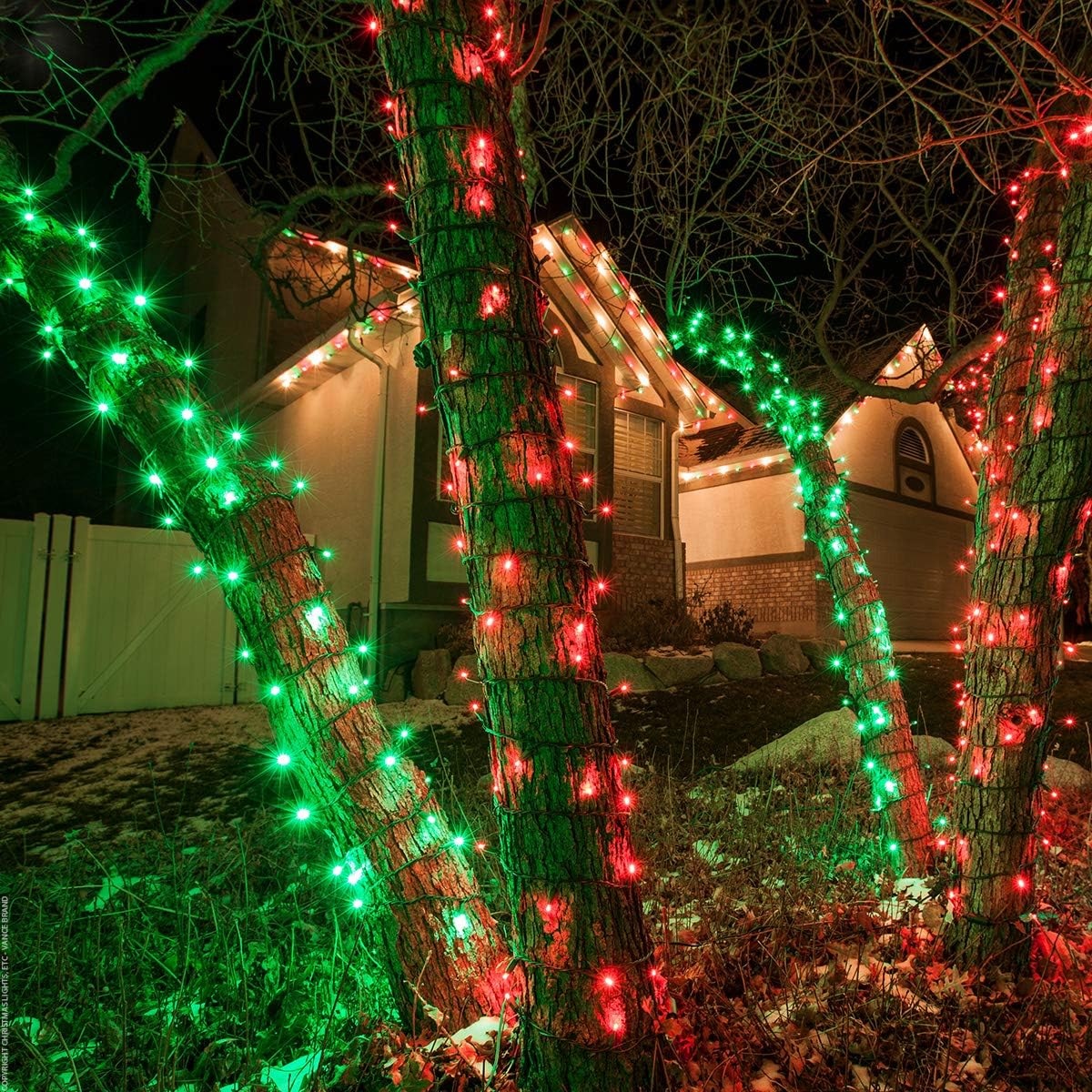 5mm wide angle string lights in red and green wrapped around tree trunks in a front yard.