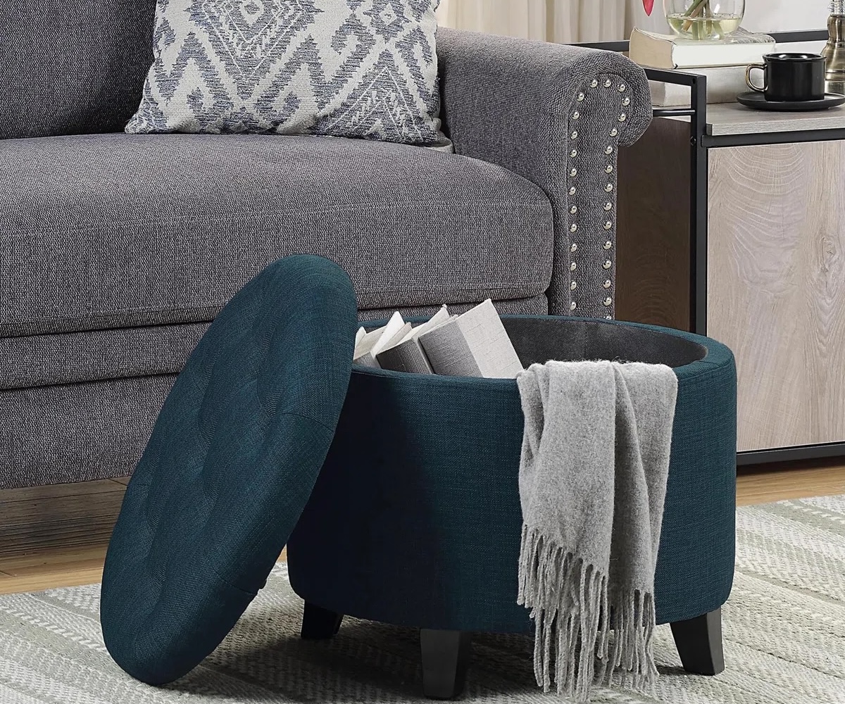 Avers Upholstered Ottoman in open revealing hidden storage in a small living room