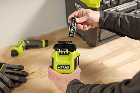 Hands placing battery in Ryobi USB Lithium battery charger.