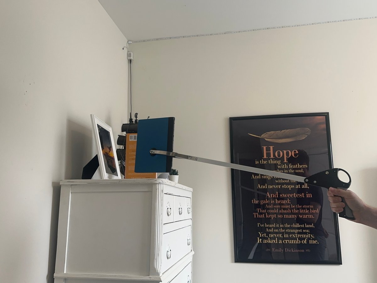 Person using Vive suction cup grabber tool to get book from dresser