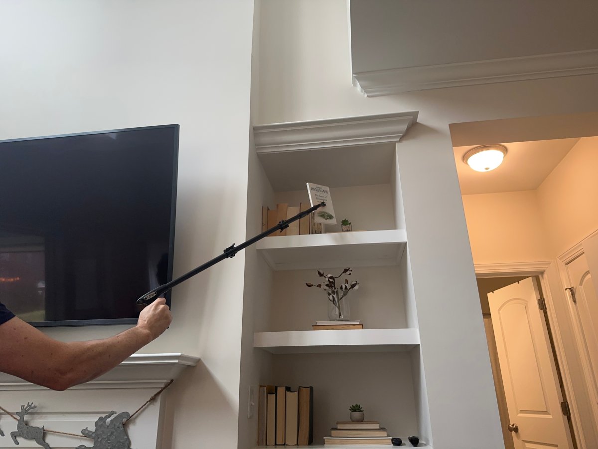 Person using suction cup grabber to get book from tall bookshelf