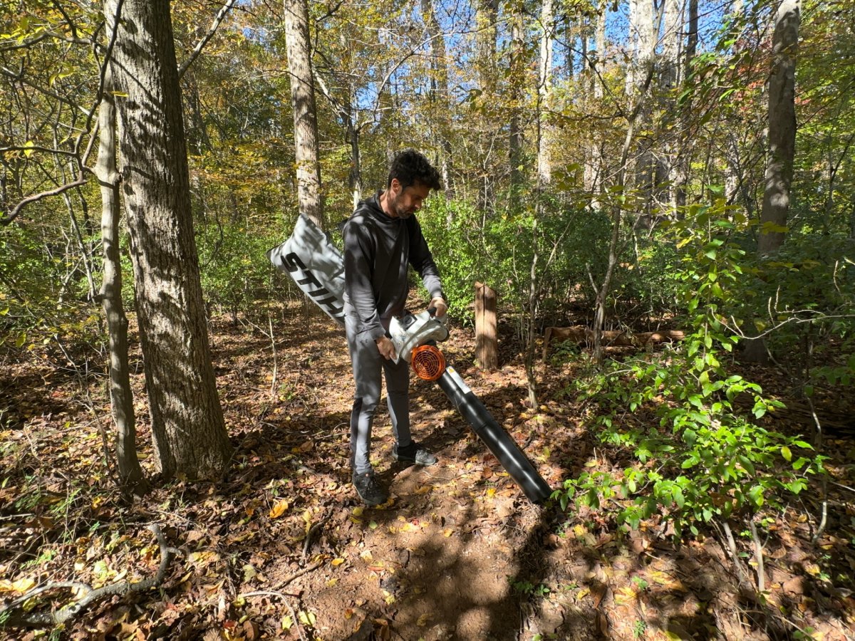 Man using leaf vacuums in a forest